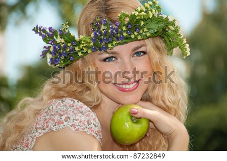 Long-haired beautiful smile girl 
with flower diadem hold apple in hand