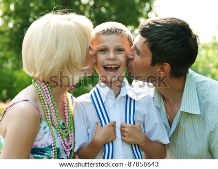 Happy family: mum and dad kiss a son