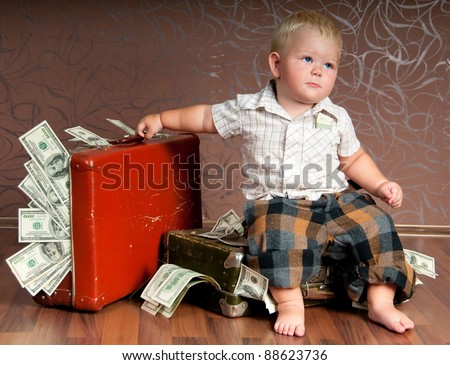 Cute little boy sitting ?n a suitcase with the money