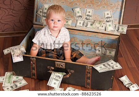 Cute little boy sitting in a suitcase with the money