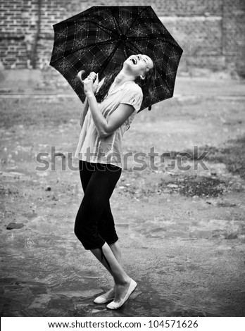 Happy woman under rain with umbrella
