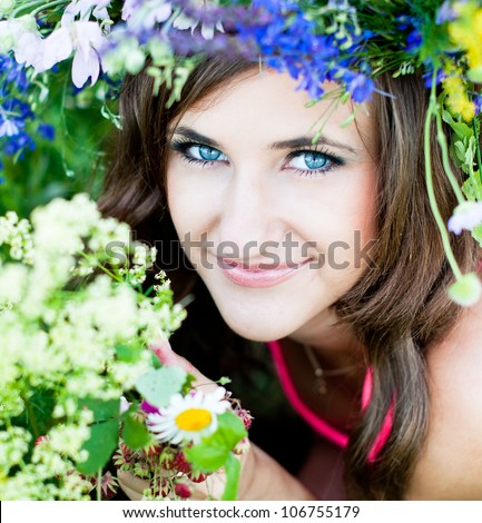 Portrait of smiling young woman in flower wreath at the green forest