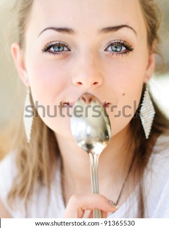 Young beautiful woman with spoon on her mouth