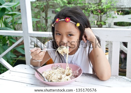 Asia girl  eating spaghetti cream with a fork.