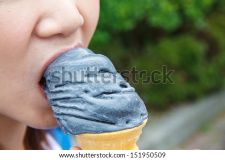 Girl eating black ice cream, valley Ashi, Japan.