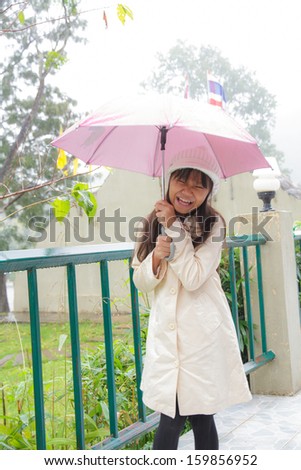 Happy girl an umbrella in the rain.