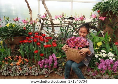 Young Asian woman sitting holding a basket of flowers.