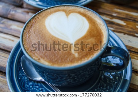 Hot coffee drawing hearts in blue glass.