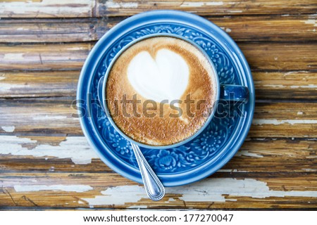 Hot coffee drawing hearts in blue glass.
