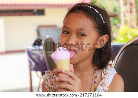 Asian girl eating Ice Cream Cone in restaurant.