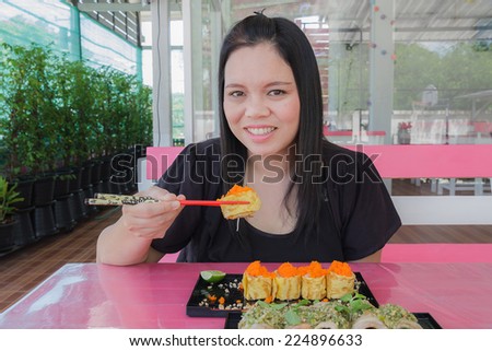 Girl eat sushi egg and bacon chili sauce in restaurant