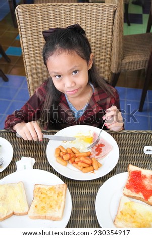 Asia children girl eating breakfast in restaurant.