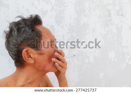 Asian old man smoking cigarette. Face filled with wrinkles.