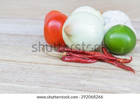 Thailand herb ingredients: lime, lemon, tomato, onion, garlic and chili on wood table.
