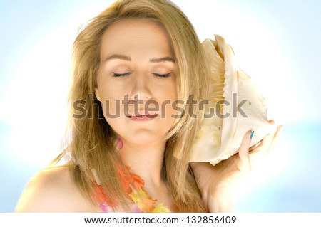 Beautiful portrait of a blond woman on the exotic beach with a shell