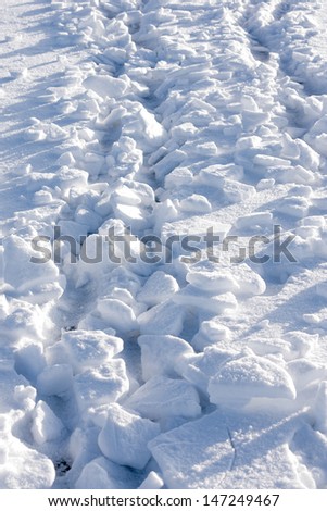 Heap of broken pieces of snow and ice under the bright sunlight, vertical view