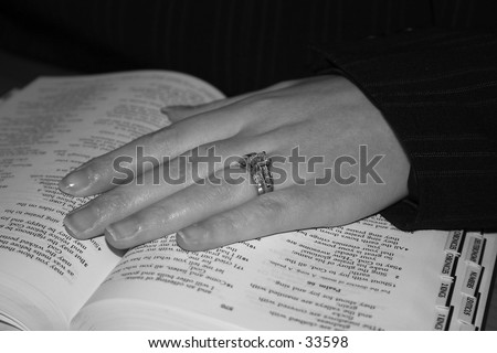 Woman\'s hand on text of Bible.  On largest resolution image you can read portions of the text.
