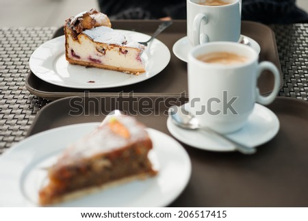 Freshly baked cheese cake with a slice of carrot cake in the foreground