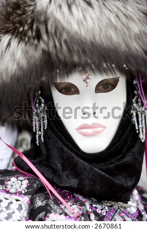 Lady at the Venice carnival wearing a fox hair hat, jewelery and a white mask