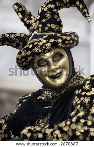 A joker at the Venice carnival in St. Mark\'s Square in a gold and black costume