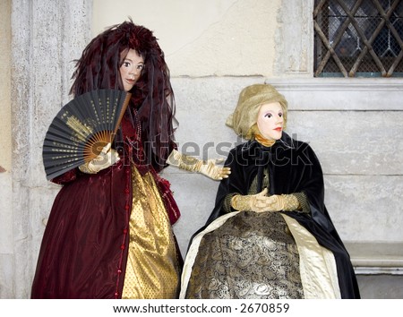 Two people posing in Venetian clothing in St Mark's Square - stock