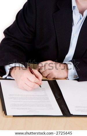 A businessman in a blue suit and no tie signing a contract