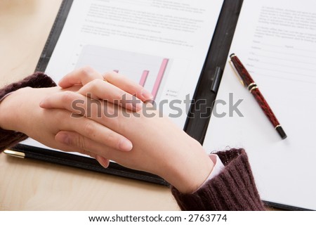 A woman with crossed hands reading through the latest financial figures