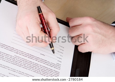 A business man with a red and black pen about to sign a document