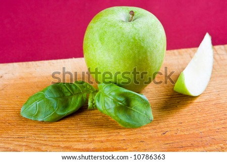 A green apple with a freshly cut apple slice
