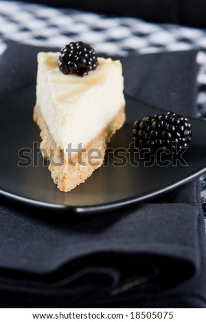 Homemade lemon cheesecake with blackberries on a black cloth
