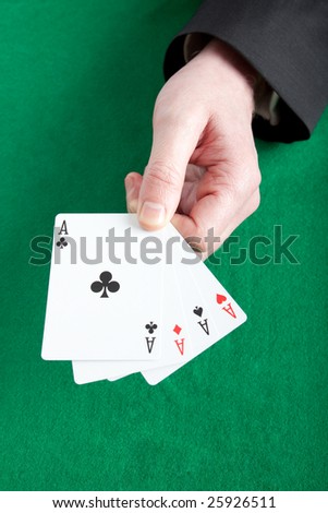Card player holding all four aces on a green cloth