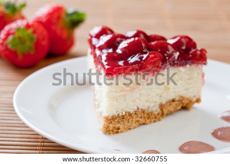 Slice of delicious strawberry cheese cake on a white plate with fresh strawberries in the background