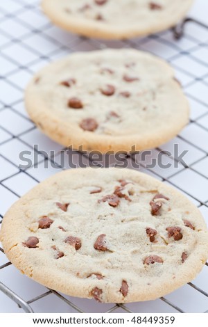 Line of three large chocolate chip cookies on a cooling tray