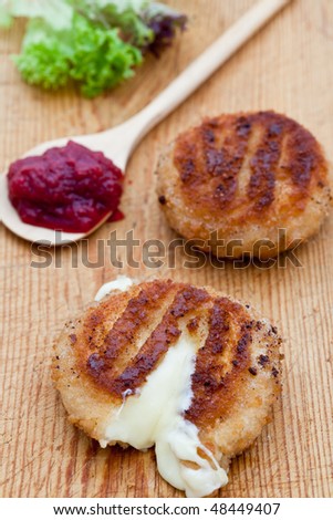Two fried camembert cheeses in bread crumbs with melted cheese running out