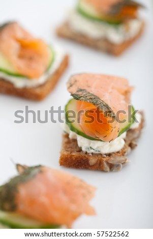 Appetizer of smoked salmon, cucumber and cream cheese on a slice of brown bread. Shallow DOF