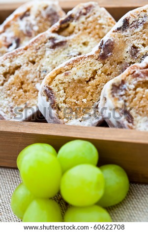 Slices of stollen cake in a wooden box with fresh green grapes. Shallow DOF