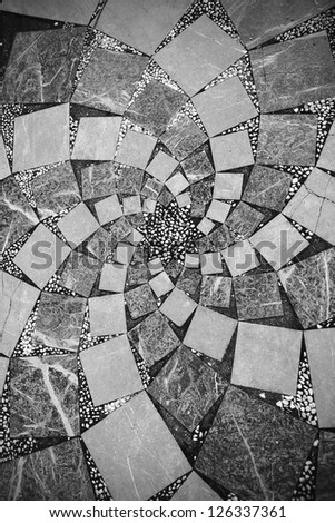 Mosaic tiles in spiral shape on the floor of a square city in black and white