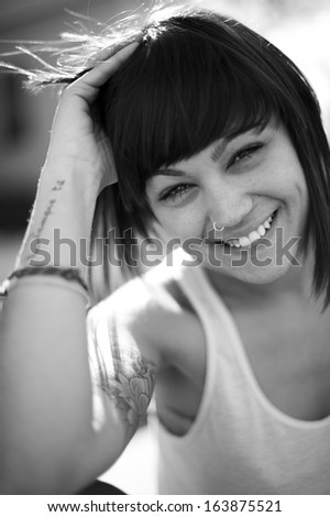 Portrait of beautiful young girl in urban background. Caucasian woman smiling staring at camera. Black and white image.