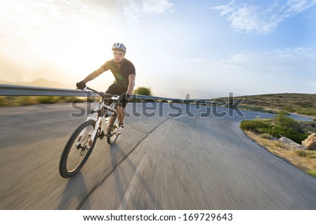 Cyclist Man Riding Mountain Bike In Sunny Day On A Mountain Road. Image With Flare.