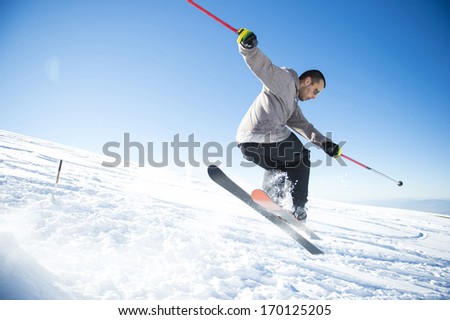 Freestyle ski jumper with crossed skis in snowy mountains