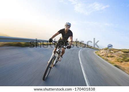 Cyclist Man Riding Mountain Bike In Sunny Day On A Mountain Road