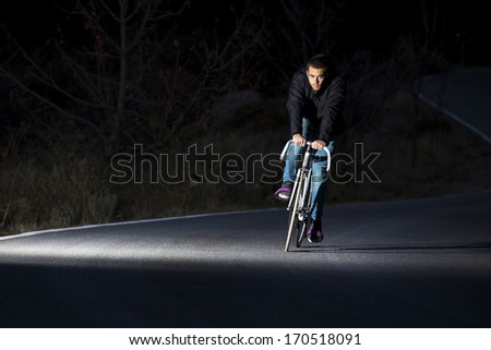 Cyclist man riding fixed gear sport bike in sunny day on a mountain road. Nocturne image.