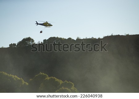 GRANADA, AUGUST 28: Fire fighting Helicopter, with bambi basket, during a fire fighting in the bush. August 28, 2014, Granada, Spain.