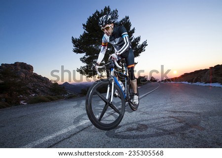Cyclist man riding mountain bike at sunset on a mountain road