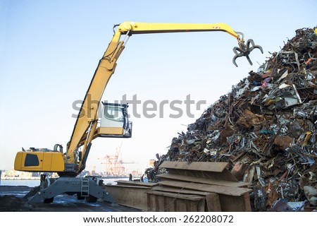 Large tracked excavator working a steel pile at a metal recycle yard