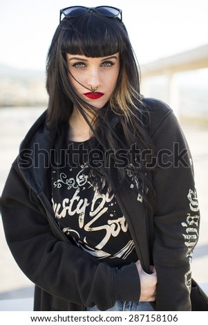Portrait of a young beautiful woman in a urban background wearing black clothing looking at camera