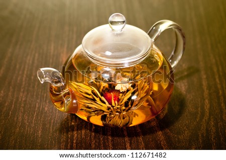 Blooming tea in glass tea pot on a wooden table