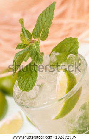Lime Mojito close up with a straw hat background,  a Cuban cocktail made with cuban rum, lime, sugar and a splash of soda