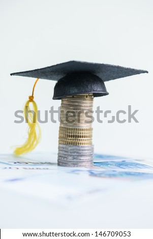 Saving for higher education concept with Mortarboard on top of a stack of Euro coins and 20 Euro banknotes