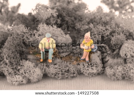 Colorful miniature elderly man and woman chatting in the garden with black and white background